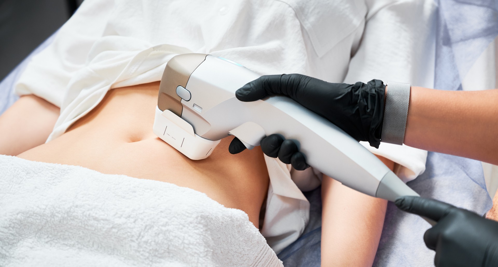 Young woman having abdominal lifting procedure in clinic.