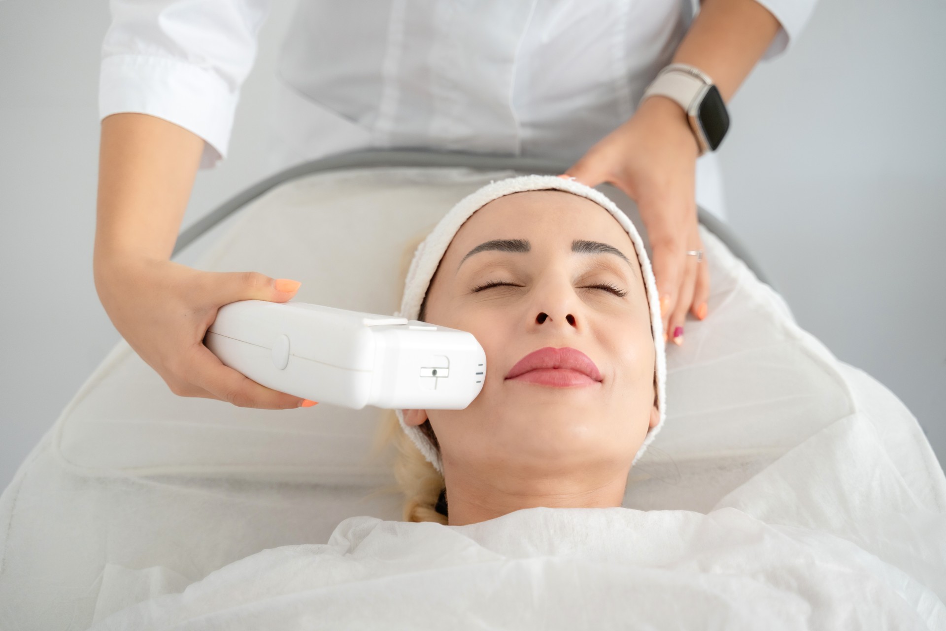 Woman getting laser facial lifting therapy in beauty salon