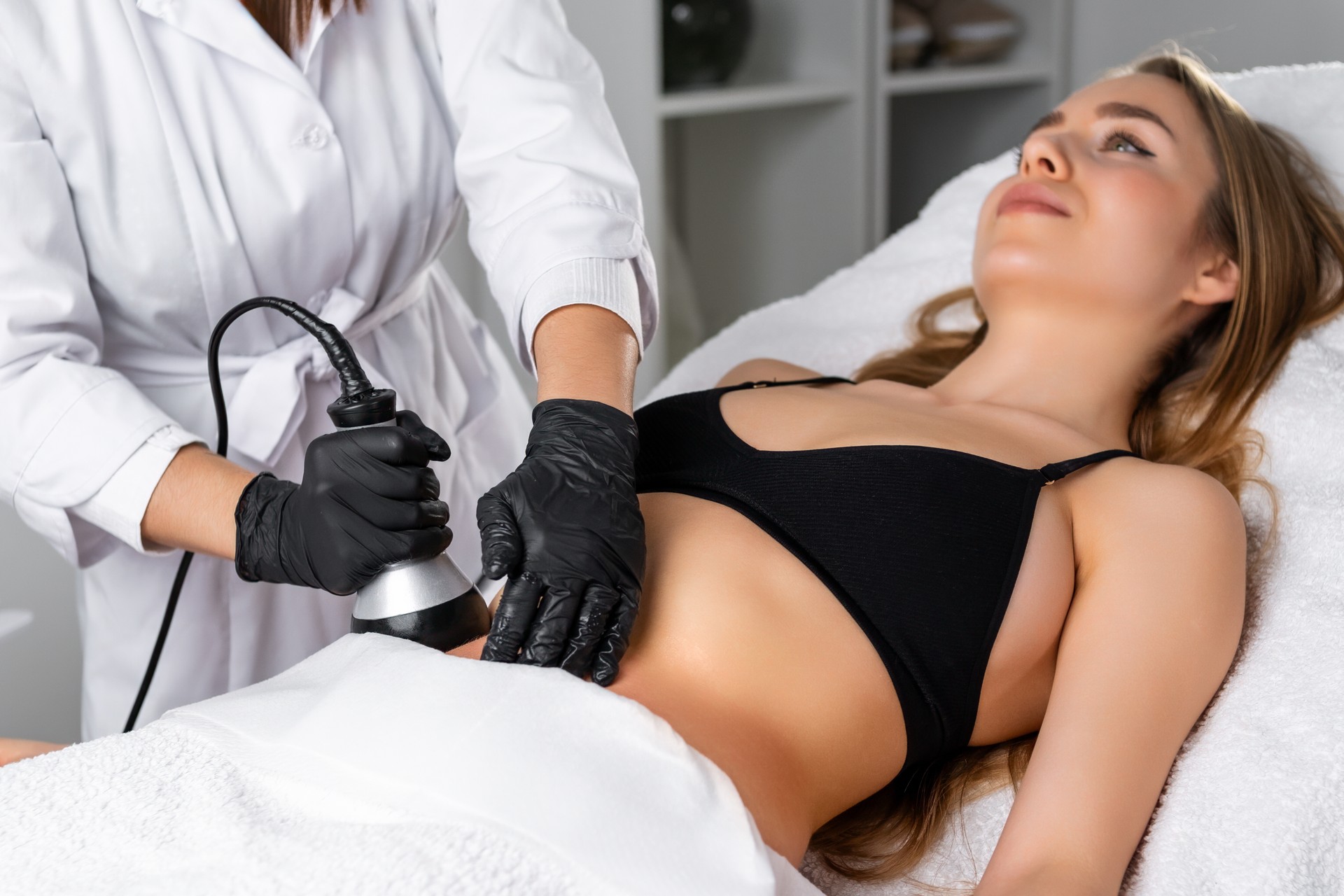 Young woman undergoes ultrasound cavitation procedure for skin tightening